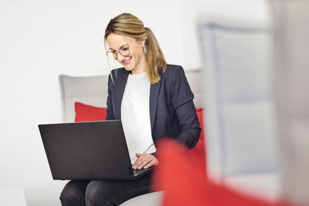 Celine Spitz pracuje na swoim laptopie na sofie w salonie kwsoft.