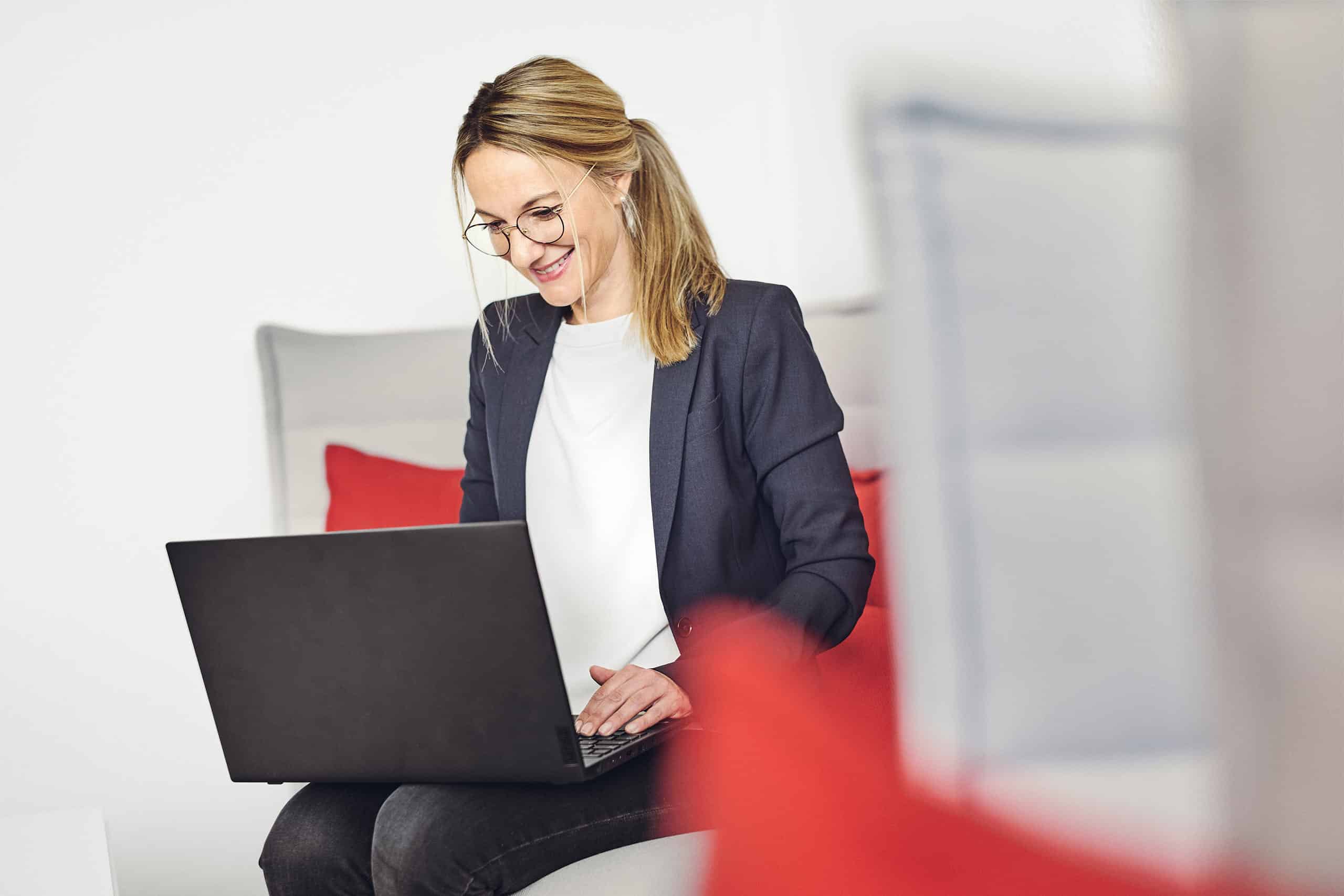 Celine Spitz pracuje na swoim laptopie na sofie w salonie kwsoft.